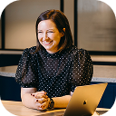 Clubworx CEO, Emily Smart, smiles while sitting at a desk.