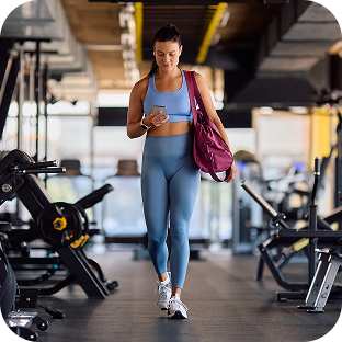 Woman checks payment status on her phone while walking out of gym.