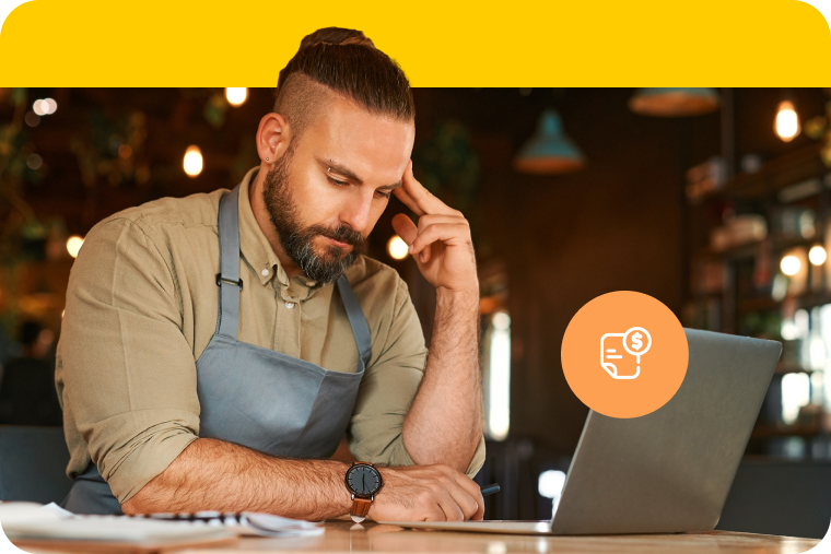 Restaurant owner pauses in deep thought while working on laptop