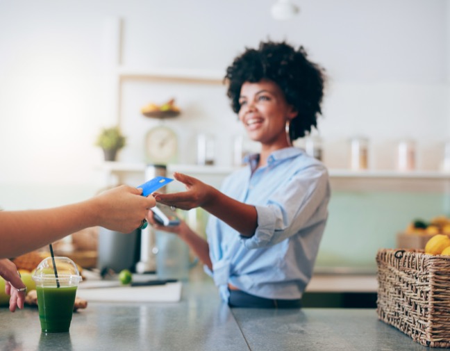Customer hands cashier a credit card to pay for their order in a smoothie shop