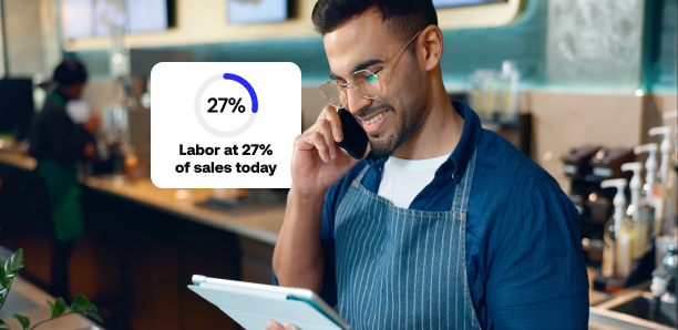 Busy restaurant owner looks at a labor report on a tablet, and a mock dashboard card (“Labor at 27% of sales today”) appears over the image