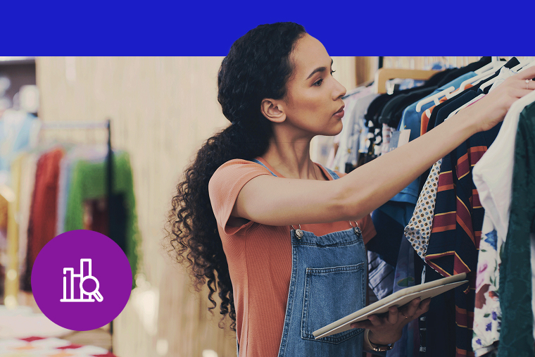 Person browsing through clothes on rack while holding tablet