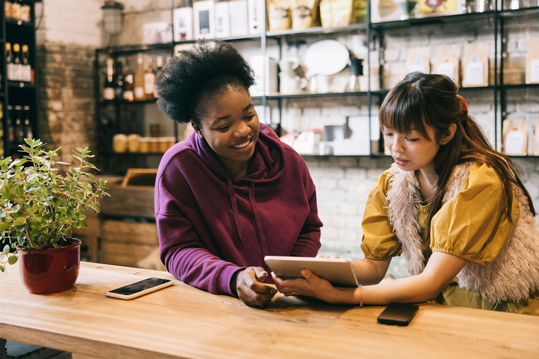 Two small business employees collaborating over tablet behind counter in retail shop