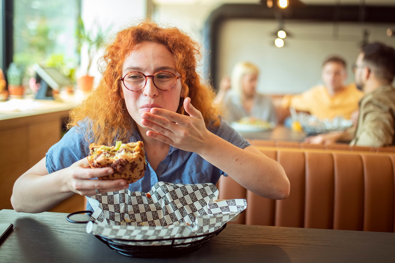 Customer eating sandwich while seated in booth in quick-service restaurant