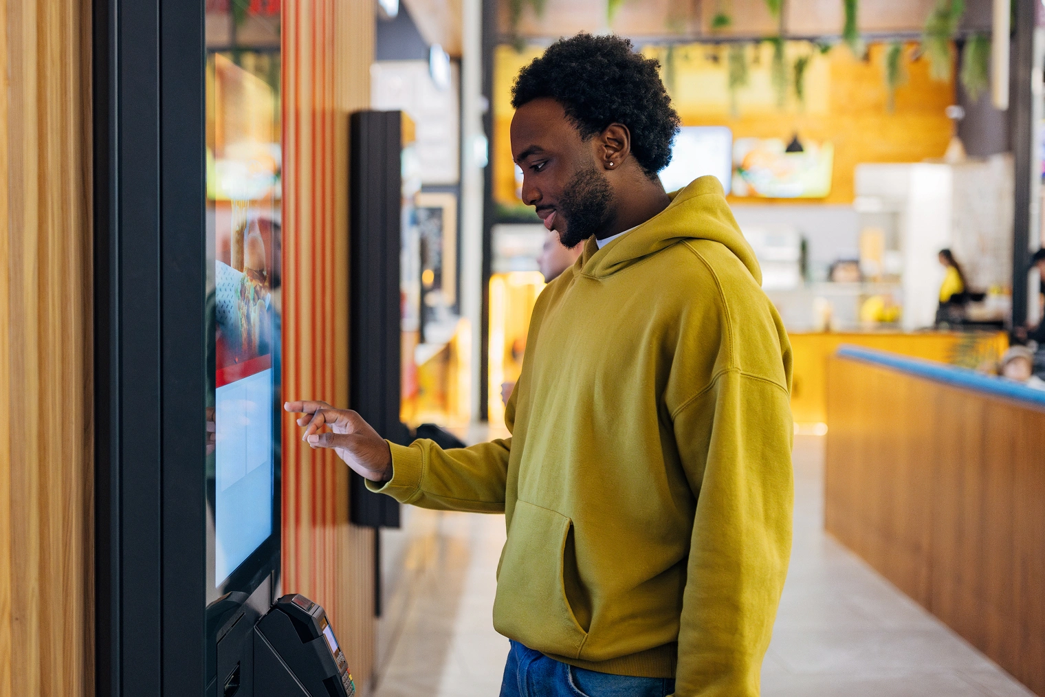 Customer using Genius self-service kiosk to order food at quick-service restaurant