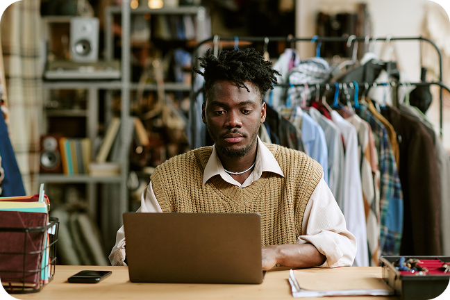 Image of seated person working on laptop at desk in clothing store