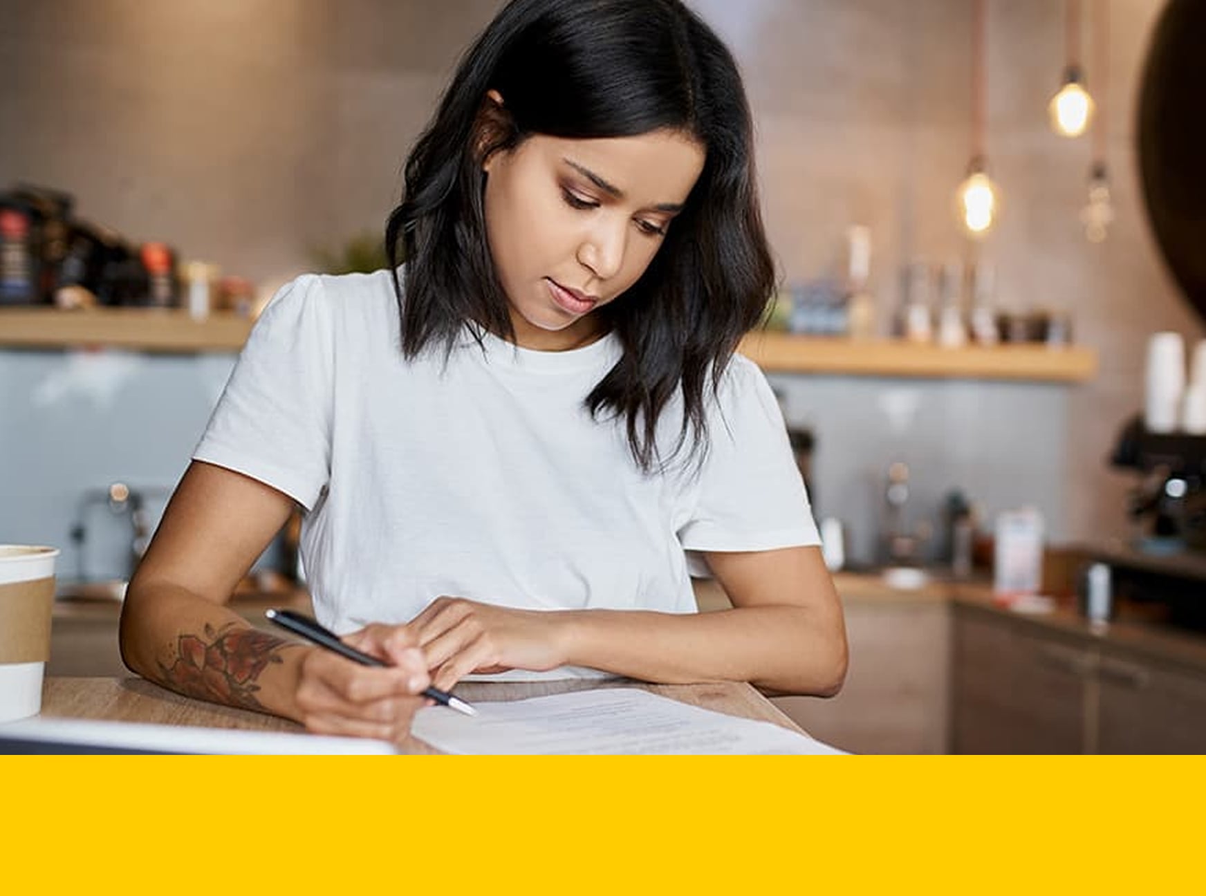 Seated owner of small business reviews paperwork with mechanical pencil in hand.