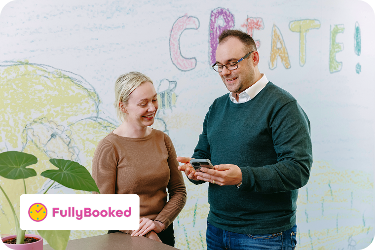 Two adults in a childcare centre discuss how Ezidebit by Global Payments integrates payments with FullyBooked’s software.