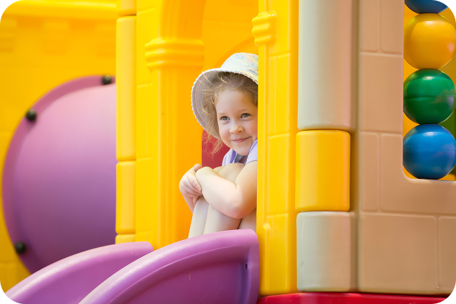 A toddler sits at the top of a yellow slide.