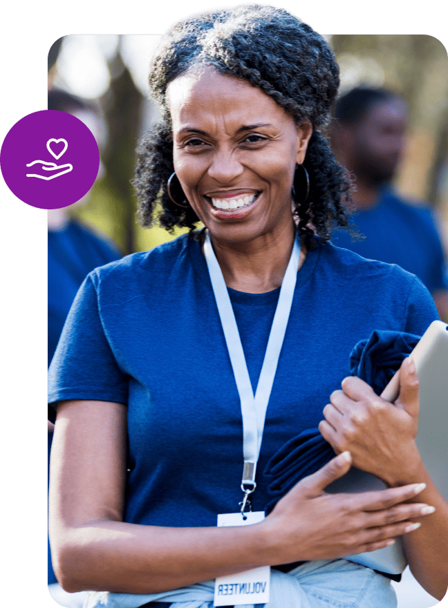 Woman wearing a volunteer lanyard holding a tablet near a purple heart icon.