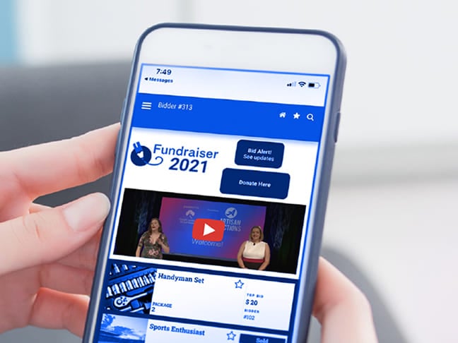 Personne tenant un smartphone affichant une application mobile pour une vente aux enchères caritative en ligne.