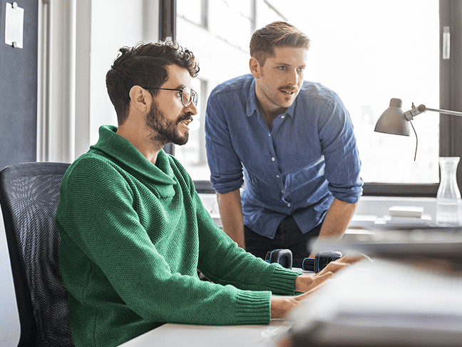Two male colleagues looking at a computer screen together in an office.