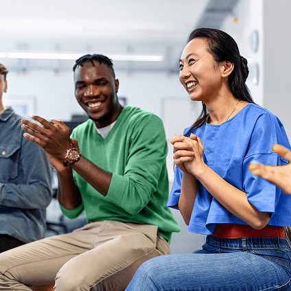 Man and woman sitting next to each other and clapping in casual business environment