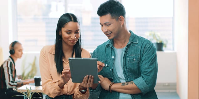Man and woman reviewing content on a digital tablet together.