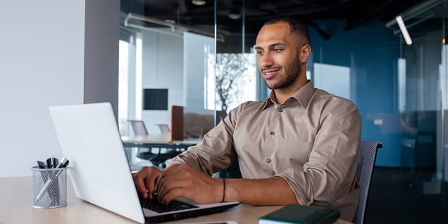 Professional man working on a laptop computer in a modern office space.
