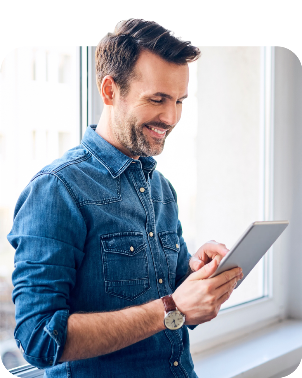 Man in office environment looking at tablet and smiling