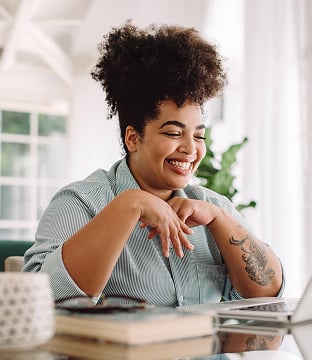 A smiling customer shops online at a laptop.