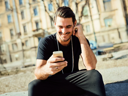 A smiling person looks at their phone.