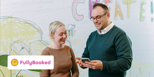 Man and woman smiling and looking at mobile device