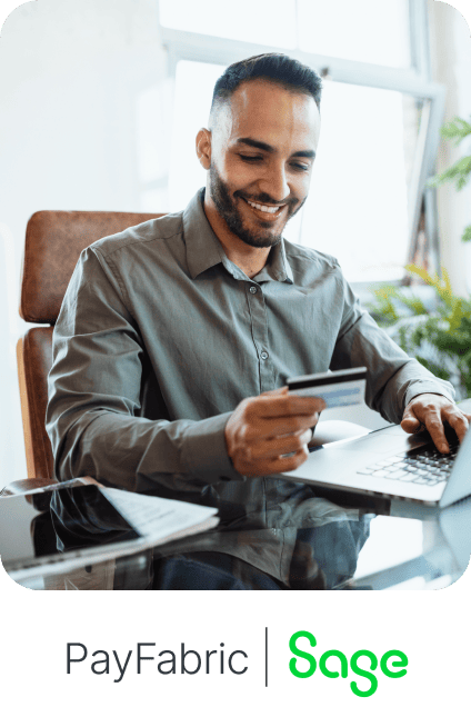 Man holding credit card using laptop above PayFabric and Sage logos.