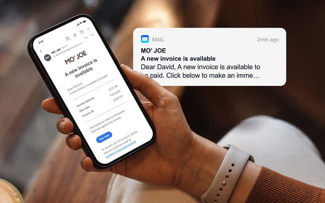 Person holding a phone showing a new invoice email with a notification popup.