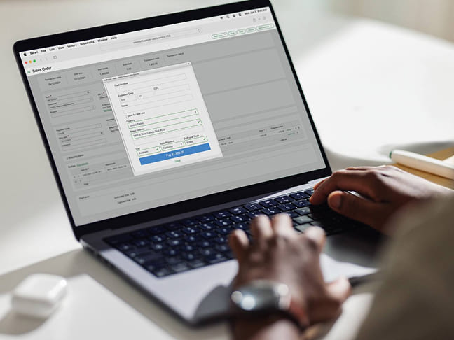 Person typing on a laptop showing an open payment processing window.