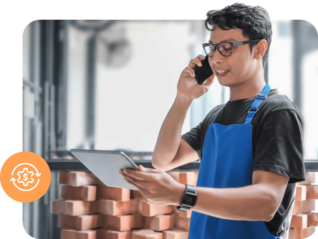 Man in a blue apron using a phone and tablet with a financial icon overlay.