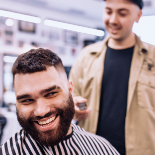 Un coiffeur coupant les cheveux d'un client souriant dans un salon de coiffure.