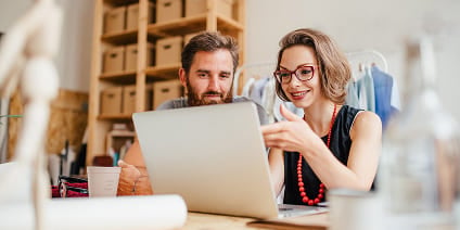 Un chef d'entreprise et un investisseur analysent les données de vente au détail sur un ordinateur portable, dans un magasin.