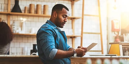 A restaurant owner checks his inventory from a mobile tablet.