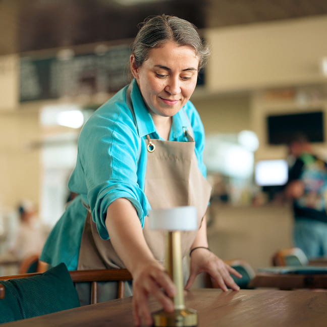 A restaurant staff member sets a table.