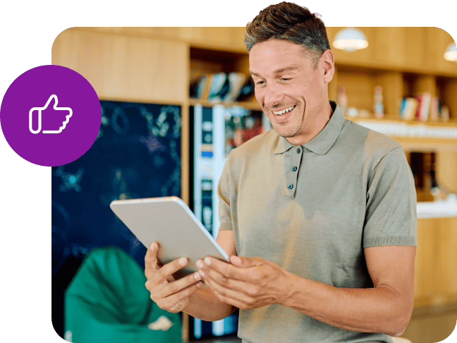 Homme souriant tenant une tablette affichant une icône de pouce levé violet en surimpression.