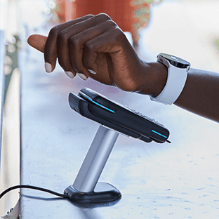 A customer makes a contactless payment with a white wearable watch.
