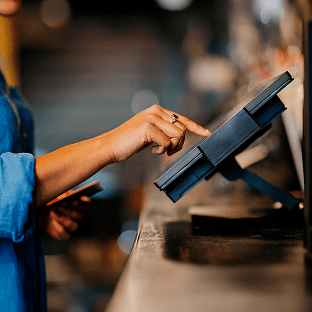 Customer keys in card digits on a countertop card machine.
