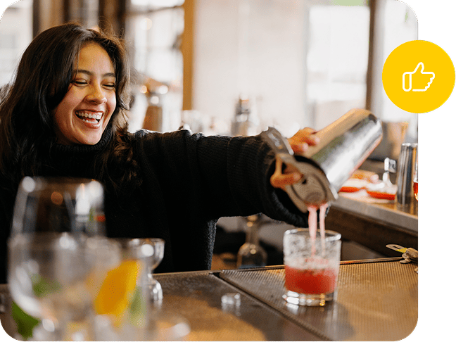 Bartender mixes a Cosmopolitan and pours it into a cocktail glass.