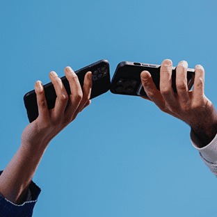 Two phones held by two hands touching mid-air.