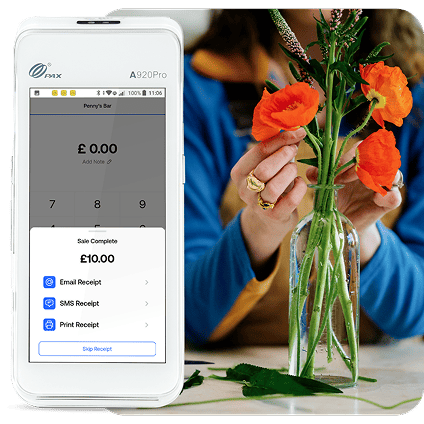 Woman arranges orange begonias in a glass vase next to a PAX A920 card machine.