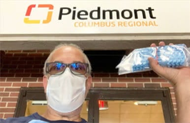 Man wearing a mask holding a bag of face masks outside Piedmont Columbus Regional.