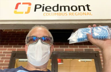 Un homme portant un masque tient un sac de masques à l'extérieur de Piedmont Columbus Regional.