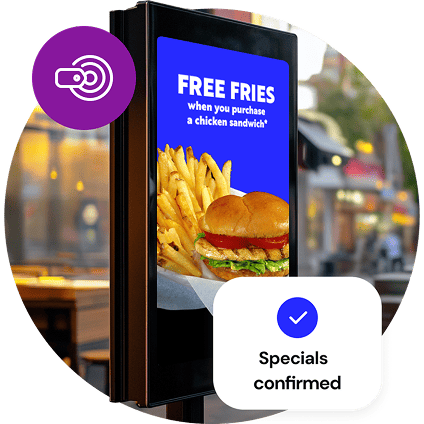 A freestanding, outdoor digital menu board shows a free fries special, while a small, purple circle graphic with a pricing icon overlays the image at the top and a graphic reading “Specials confirmed” overlays the bottom of the image.