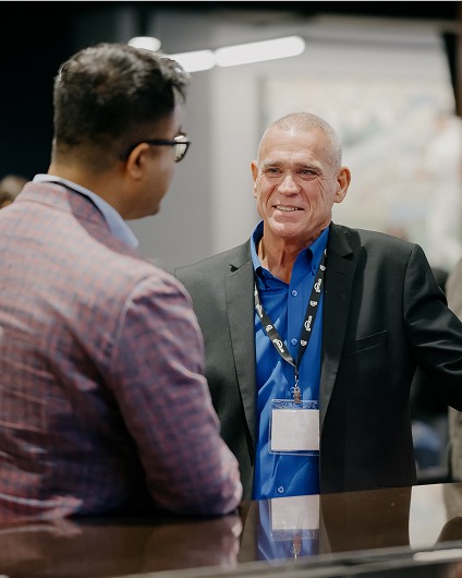 A man wearing a Global Payments lanyard speaks with an attendee at a Wholesale ISO tradeshow event.
