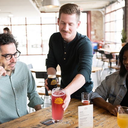 A waiter puts drinks down on a table in front of two restaurant guests.