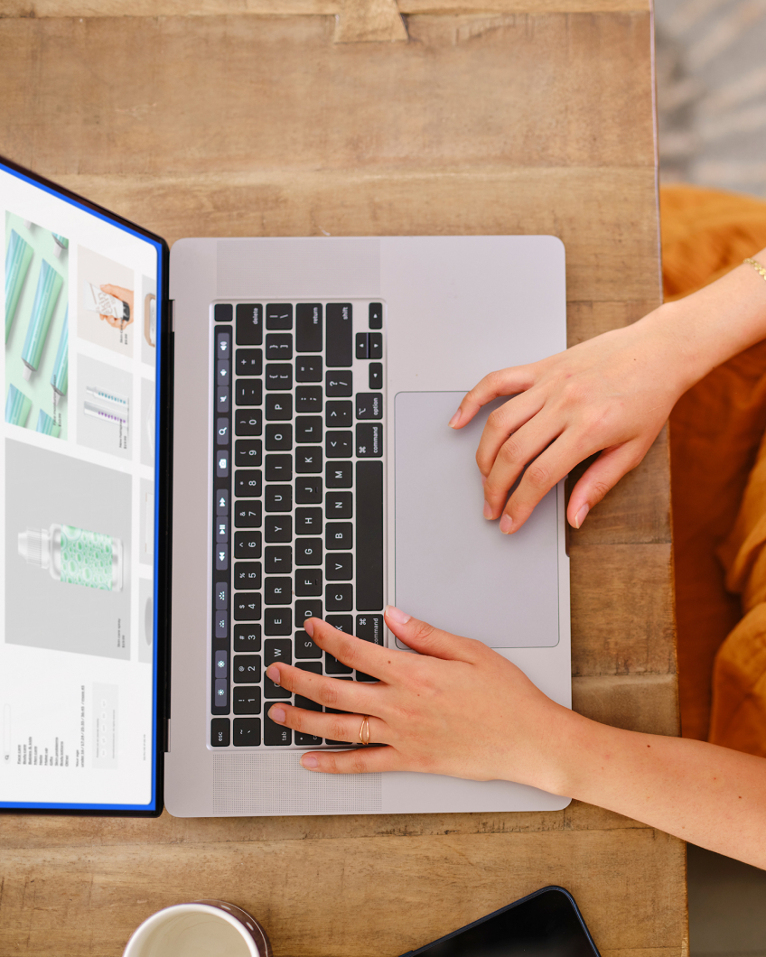 A customer’s hands tap on a laptop, which displays a shop site.