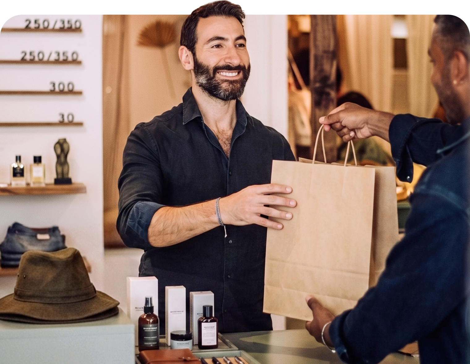 A retail shopkeeper hands a large bag to a smiling customer