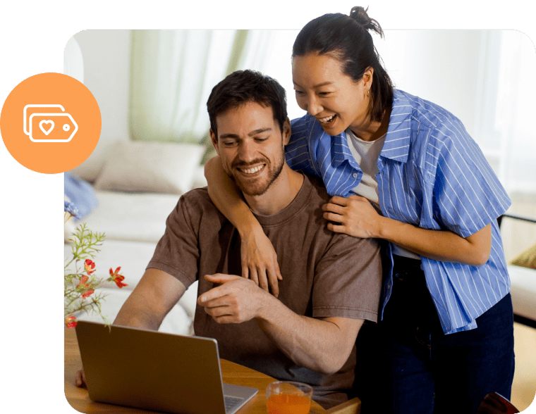 A smiling couple shopping or browsing online together on a laptop at home