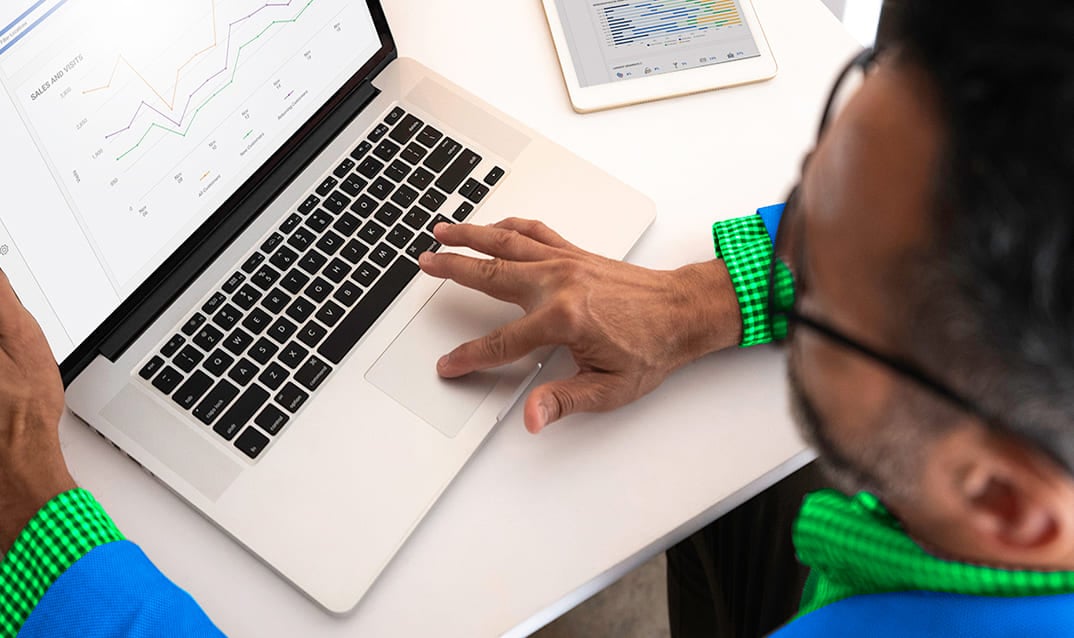 Overhead view of a person using a laptop displaying sales line graphs