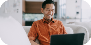 Man smiling sitting on couch and looking at laptop