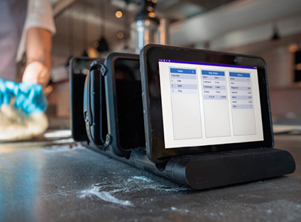 A person uses Genius Enterprise POS software on a touchscreen device.