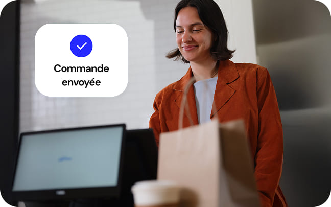 Un client sourit après avoir finalisé sa commande sur un système de point de vente Genius Enterprise.