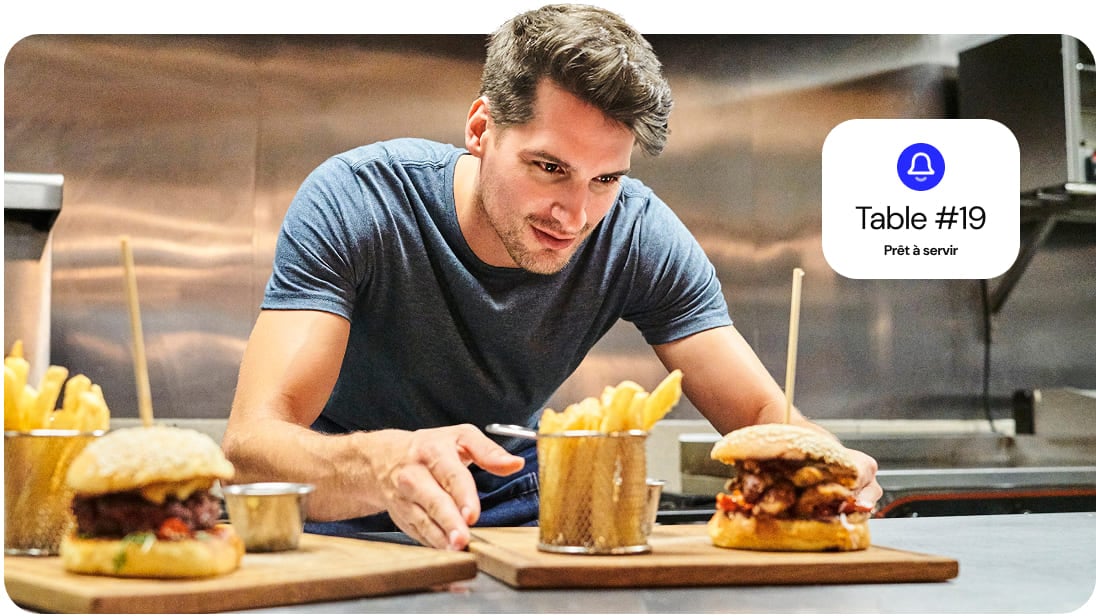 Un serveur récupère un plat en cuisine pour le livrer à un client.